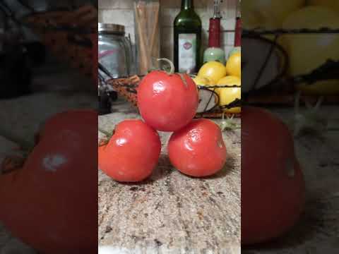 Tomato falls off two other tomatoes then rolls off the counter